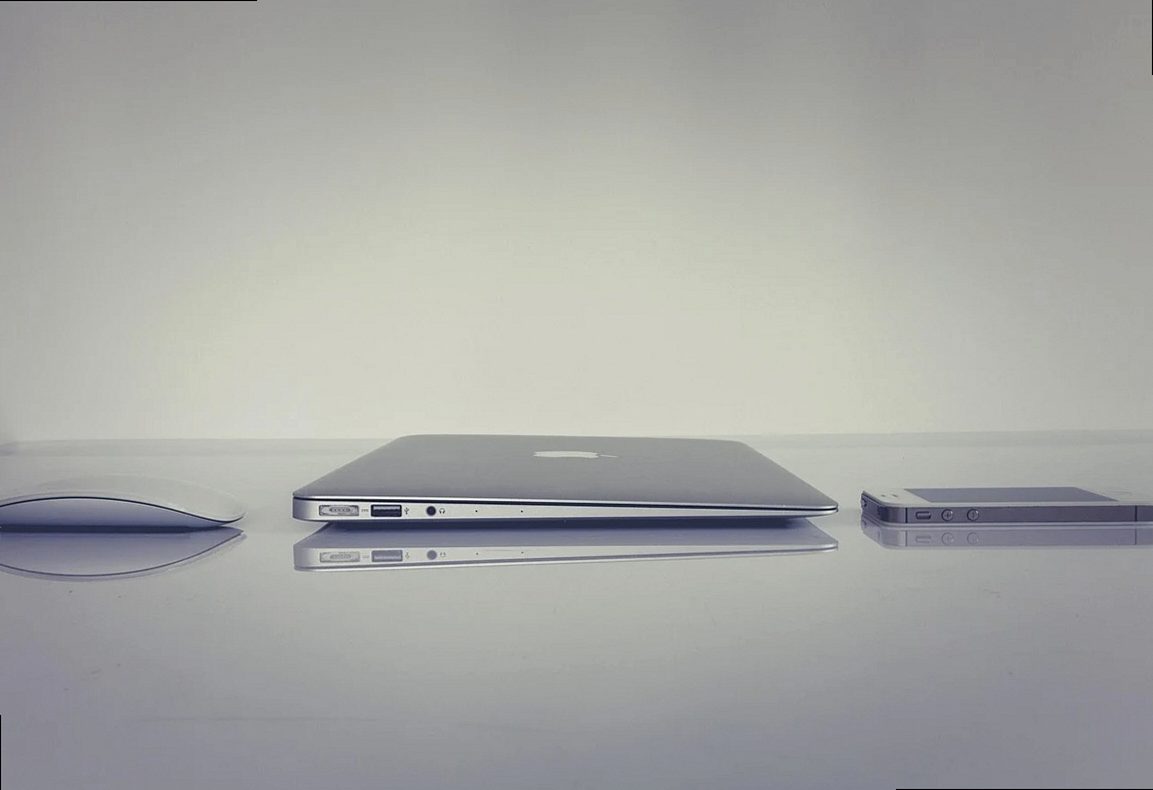 オフィス、MacBook、iPhone、Apple製品が並ぶミニマルなホームオフィスで作業するフリーランスデザイナーのデスク